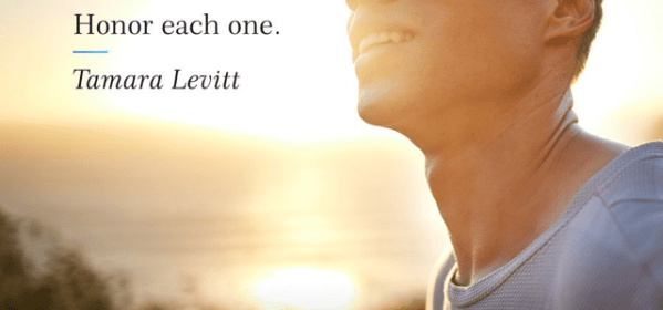 A person stands outdoors at sunset, looking slightly upward with a calm, hopeful expression. Warm sunlight illuminates her face, with the ocean and horizon softly blurred in the background. Text on the left reads: “Large victories begin as small achievements. Honor each one. — Tamara Levitt.” At the bottom are the hashtags #DailyCalm and the Calm logo.